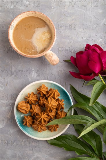 Homemade soft caramel fudge candies on blue plate and cup of coffee on gray concrete background,