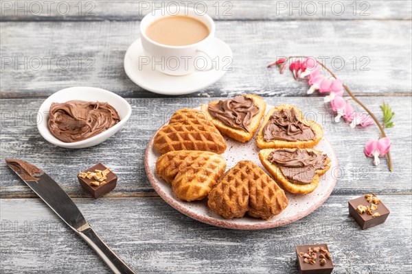 Homemade waffle with chocolate butter and cup of coffee on a gray wooden background. side view,