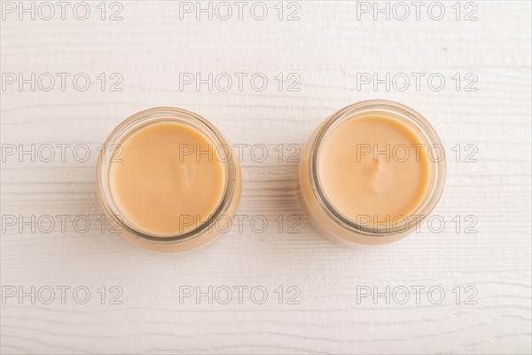 Baby puree with fruits mix, apple, banana infant formula in glass jar on white wooden background.