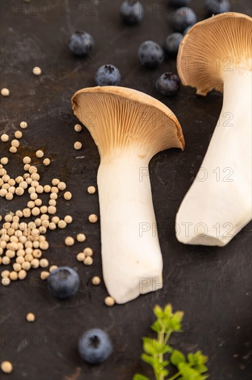 King Oyster mushrooms or Eringi (Pleurotus eryngii) on black concrete background with blueberry,