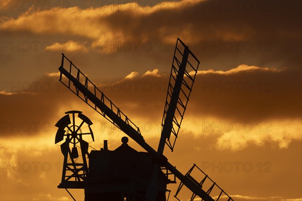 Windmill silhouetted at sunset with a red sky and clouds behind, Cley-next-to-the-sea, Norfolk,