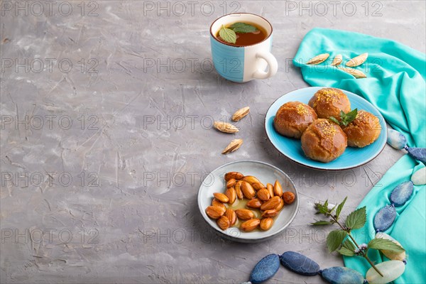 Homemade traditional turkish dessert sekerpare with almonds and honey, cup of green tea on gray