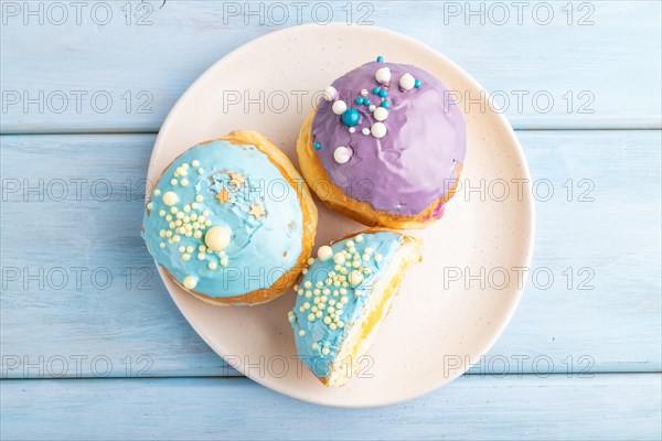 Purple and blue glazed donut on blue wooden background. top view, flat lay. Breakfast, morning,