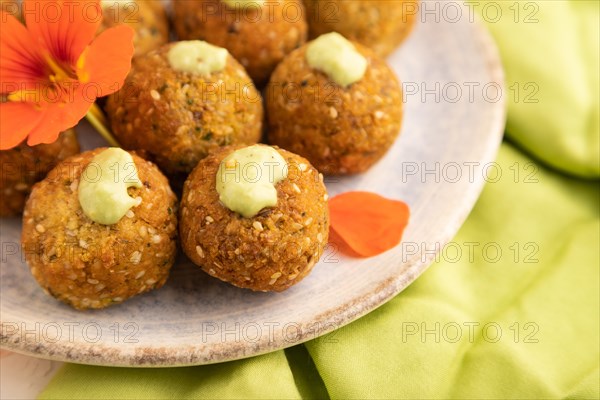 Falafel with guacamole on white concrete background and green linen textile. Side view, close up,