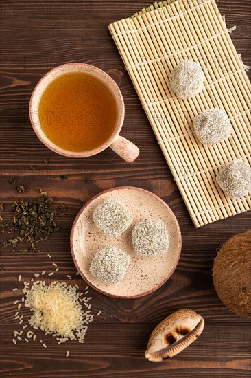Japanese rice sweet buns mochi filled with pandan and coconut jam and cup of green tea on brown