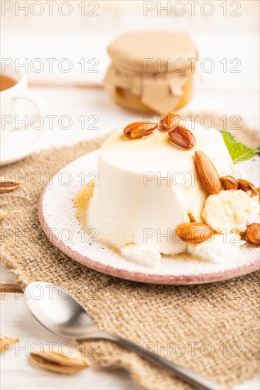 Ricotta cheese with honey and almonds on white wooden background and linen textile. side view,