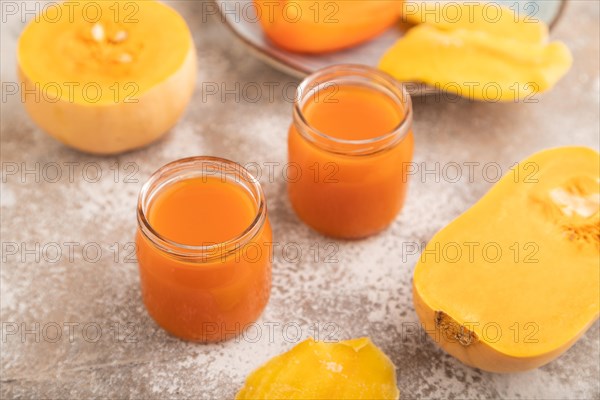 Baby puree with fruits mix, pumpkin, persimmon, mango infant formula in glass jar on brown concrete
