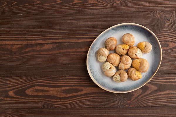 Grape (Burgundy) snails with butter and cheese on brown wooden background. Top view, flat lay, copy