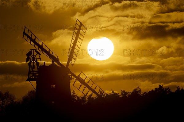 Windmill silhouetted at sunset with a red sky and clouds behind, Cley-next-to-the-sea, Norfolk,