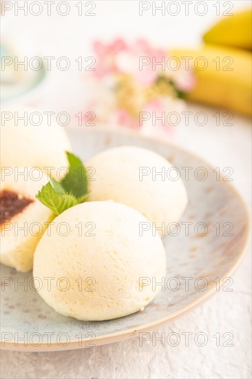 Japanese rice sweet buns mochi filled with jam and cup of coffee on a gray concrete background.