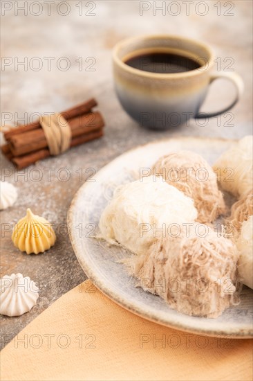 Traditional arabic sweets pishmanie and a cup of coffee on brown concrete background and orange