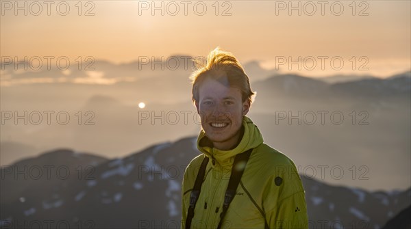 Mountaineer on the summit of Skala with cairn, view of mountain landscape and fjord Faleidfjorden,