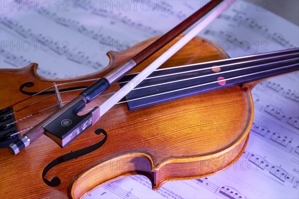 Viola with bow and music book in front of a monochrome background, studio photograph, Germany,