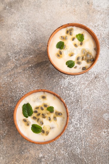 Yoghurt with granadilla and mint in clay bowl on brown concrete background. top view, flat lay,
