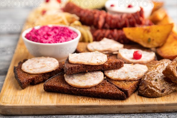 Set of snacks: sausages, toast, sauerkraut, marinated onion and cucumber, baked potato on a cutting