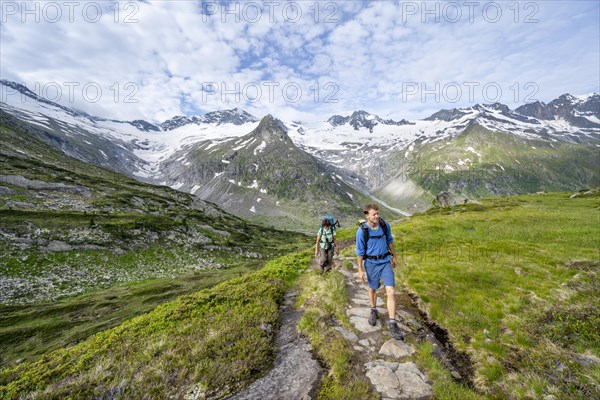 Two mountaineers on a hiking trail in a picturesque mountain landscape, mountain peaks with snow
