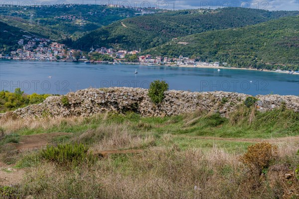 Remains of castle wall ruins with Bosphorus Strait and coastal village in background in Istanbul,