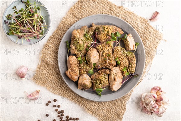 Stewed turkey fillet with garlic and sprouts of radish on white wooden background and linen textile