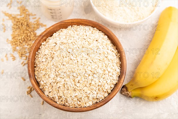 Powdered milk and oatmeal, banana baby food mix, infant formula, pacifier, bottle, spoon on gray