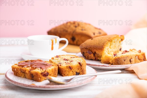 Homemade cake with raisins, almonds, soft caramel on a white and pink background. Side view, close