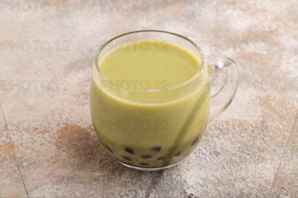 Bubble tea with pistachio and caramel in glass on brown concrete background. Healthy drink concept.