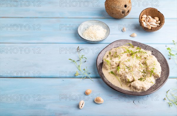 Stewed chicken fillets with coconut milk sauce and mizuna cabbage microgreen on blue wooden