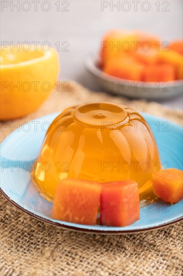Papaya and orange jelly on gray concrete background and linen textile. side view, close up,