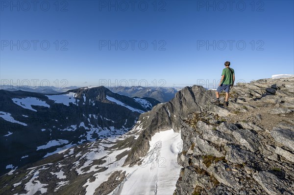 Mountain panorama, glacier remains of Skalabreen, mountaineer at the summit of Skala, Loen, Norway,
