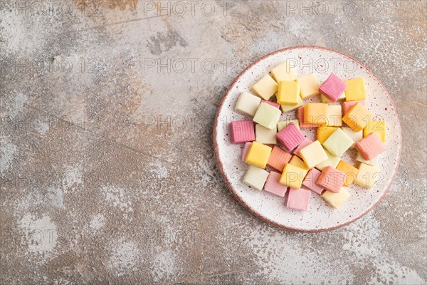 Various fruit jelly chewing candies on plate on brown concrete background. apple, banana,