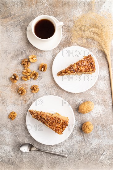 Walnut and hazelnut cake with caramel cream, cup of coffee on brown concrete background. top view,