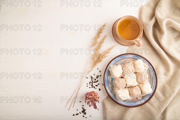 Traditional arabic sweets pishmanie and a cup of green tea on white wooden background and linen