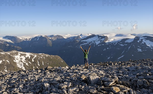 Mountain panorama with mountain peaks and Jostedalsbreen glacier, mountaineer stretches his arms in