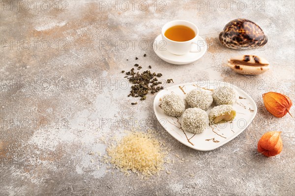 Japanese rice sweet buns mochi filled with pandan jam and cup of green tea on brown concrete