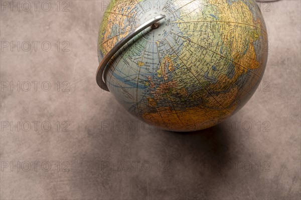 An old-fashioned globe on a grey texture with focus on the northern hemisphere, studio shot, top