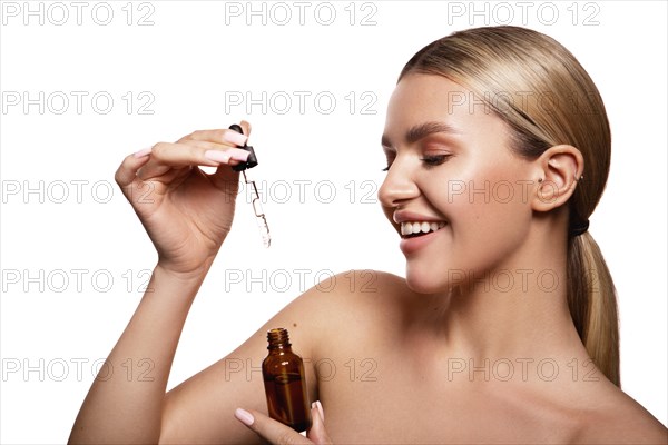 Beauty portrait of model with natural make-up holding a jar of cream. Fashion shiny highlighter on