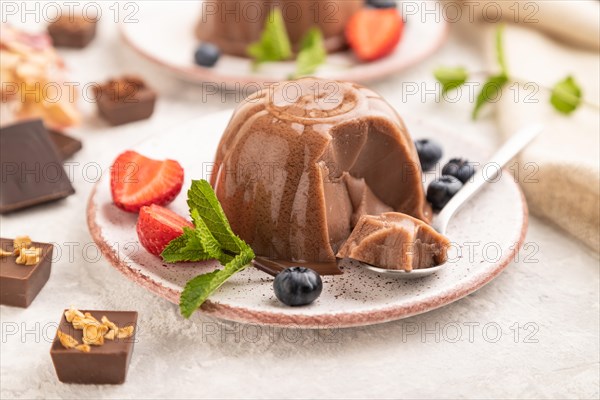 Chocolate jelly with strawberry and blueberry sliced with spoon on gray concrete background and