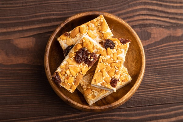 Traditional candy nougat with nuts and sesame on brown wooden background. top view, flat lay, close