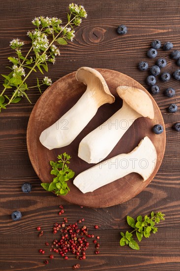 King Oyster mushrooms or Eringi (Pleurotus eryngii) on brown wooden background with blueberry,