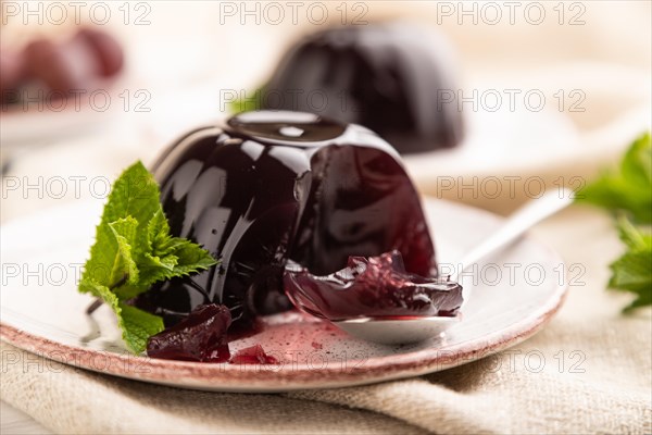 Black currant and grapes jelly on white wooden background and linen textile. side view, close up,