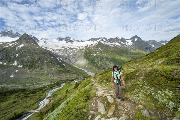 Mountaineer on hiking trail in picturesque mountain landscape, mountain peak with snow and glacier