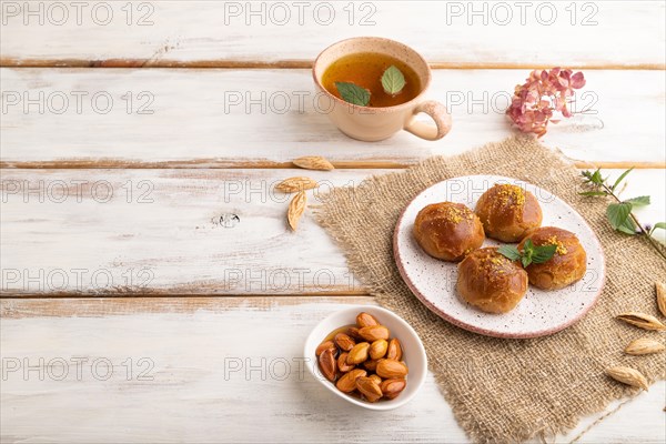 Homemade traditional turkish dessert sekerpare with almonds and honey, cup of green tea on white
