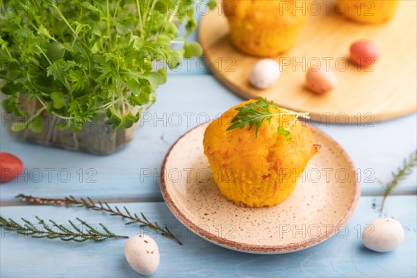 Homemade cakes with chocolate eggs and mizuna cabbage microgreen on a blue wooden background. side