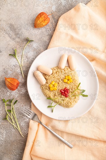 Funny mixed quinoa porridge, sweet corn, pomegranate seeds and small sausages in form of cat face