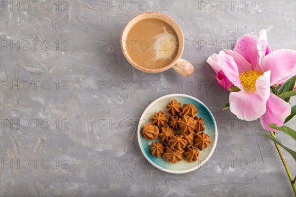 Homemade soft caramel fudge candies on blue plate and cup of coffee on gray concrete background,
