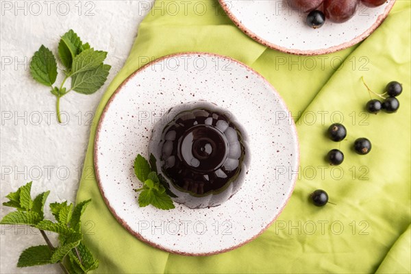 Black currant and grapes jelly on gray concrete background and green linen textile. top view, flat
