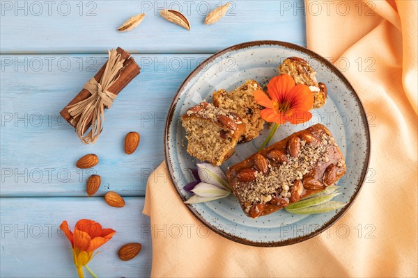 Caramel and almond cake with cup of coffee on blue wooden background and orange linen textile. top