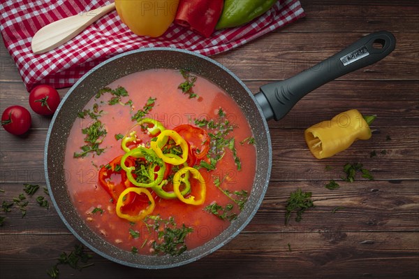 Bean soup with peppers in a pan, served with fresh herbs