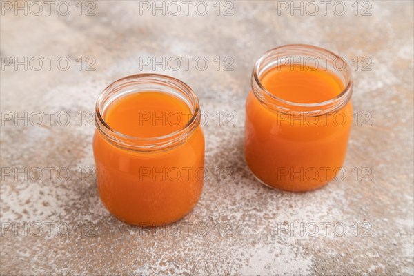 Baby puree with fruits mix, pumpkin, persimmon, mango infant formula in glass jar on brown concrete