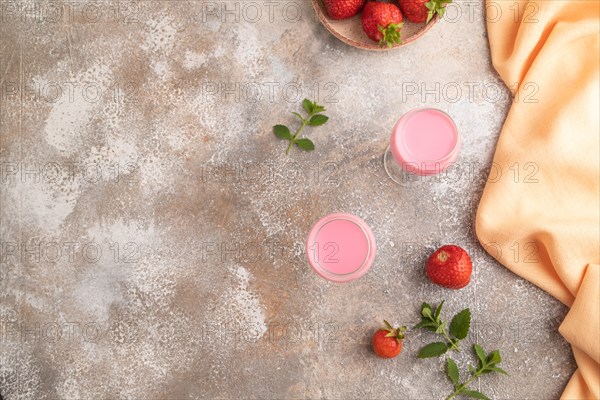 Sweet strawberry liqueur in glass on a gray concrete background and orange textile. top view, copy