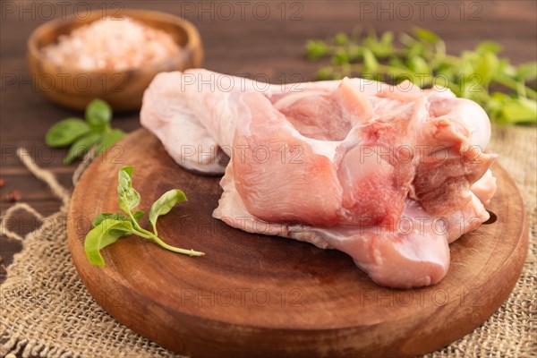 Raw turkey wing with herbs and spices on a wooden cutting board on a brown wooden background and